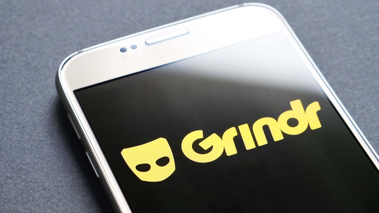 Yellow Grindr (GRND) logo displayed on smartphone against gray background