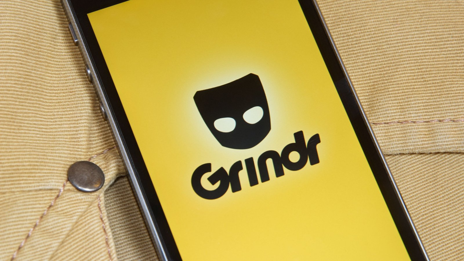 TINV Stock. The Grindr dating app on a smartphone with jeans behind it.