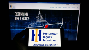 Person holding smartphone with logo of US company Huntington Ingalls Industries Inc (HII) on screen in front of website Focus on phone display