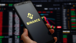 Binance mobile app running at smartphone screen with a trading page at background. Binance one of the world's leading cryptocurrency exchange and trading platform.