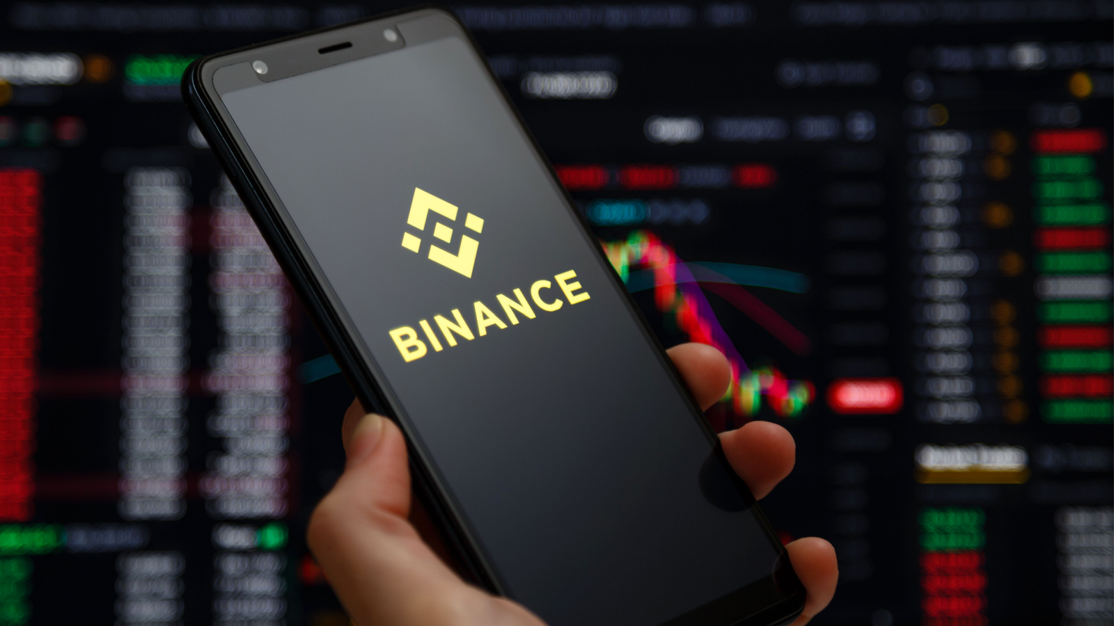 Binance.US mobile app running at smartphone screen with a trading page at background. Binance one of the world's leading cryptocurrency exchange and trading platform.
