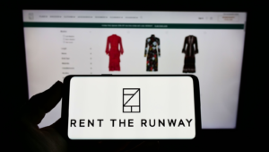 Person holding cellphone with logo of US e-commerce company Rent the Runway Inc on screen in front of business webpage Focus on phone display