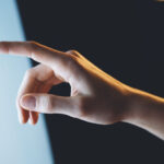 Hand with finger engaging with touchscreen, representing tech