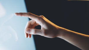 Hand with finger engaging with touchscreen, representing tech