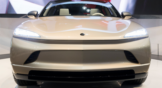 Front headlight view of a gold or tan luxury Mullen (MULN) FIVE electric vehicle SUV.