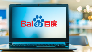 An image of a laptop on a table with the screen showing the red and blue logo for Chinese Internet company Baidu