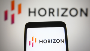 In this photo illustration Horizon Therapeutics (HZNP) logo is seen on a mobile phone and a computer screen.