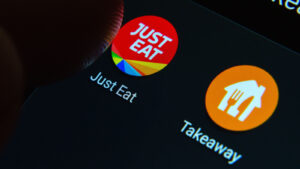 Just Eat Takeaway.com (JTKWY) アプリのロゴが黒い電話画面に表示される