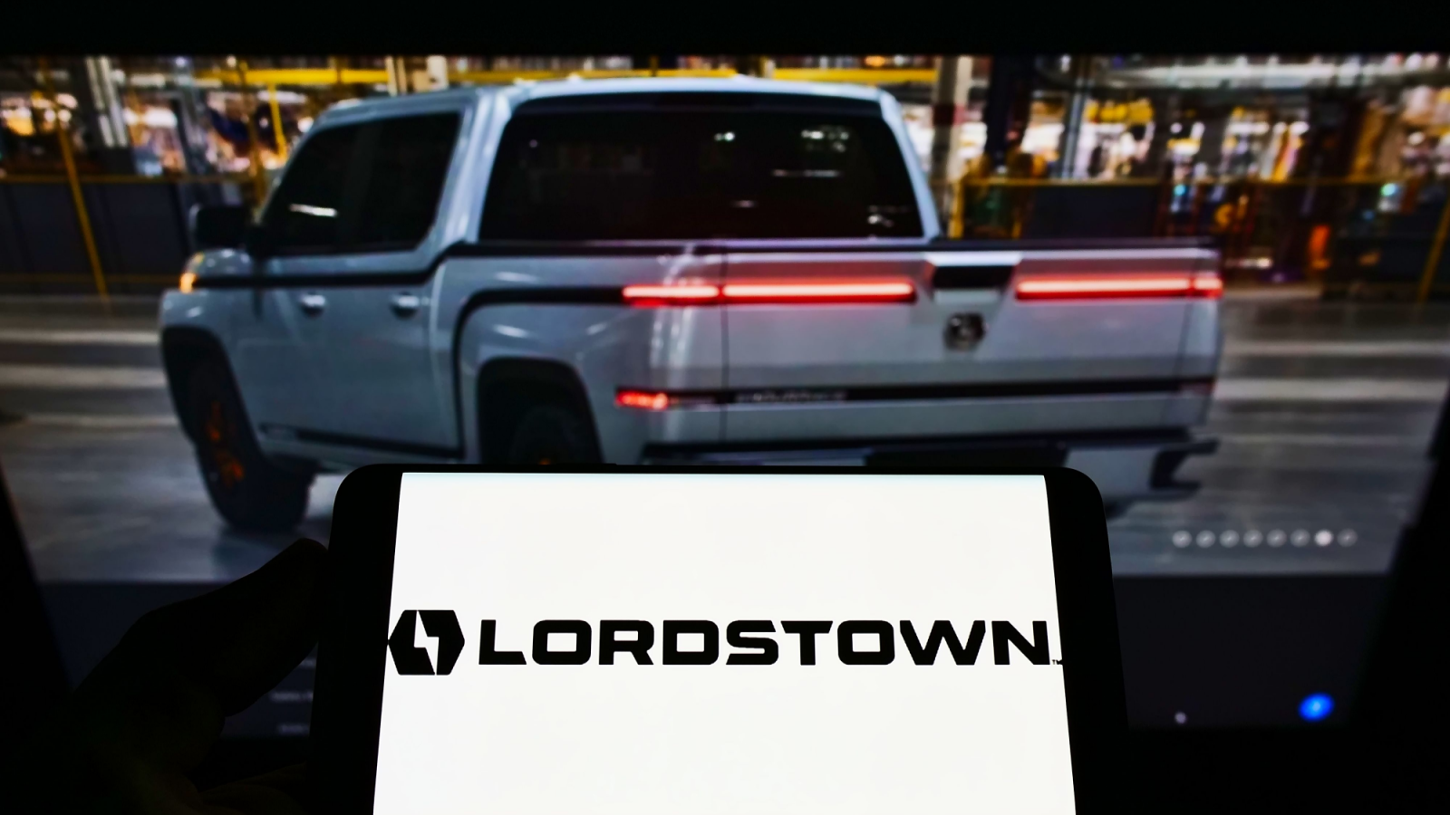 Person holding smartphone with logo of US automotive company Lordstown Motors Corporation (RIDE) on screen in front of website. Focus on phone display. Unmodified photo.