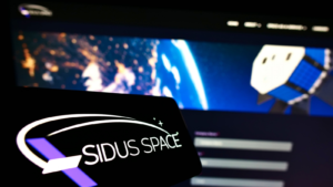 Smartphone with logo of American aerospace company Sidus Space (SIDU) on screen in front of website. Focus on center-right of phone display. Unmodified photo.