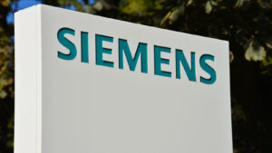 Siemens (SIEGY) sign in blue and white against green outdoor background, symbolizing SIEGY stock