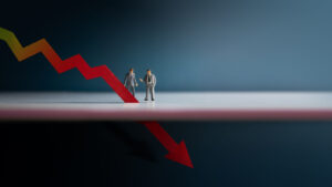 Figurines of two little men in suits looking at downward stock arrow going through the floor. overvalued stocks