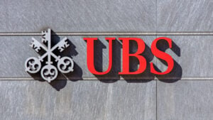 赤とグレーのロゴが付いた灰色の石の壁に UBS (UBS) 銀行の看板