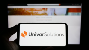 Person holding smartphone with logo of US distribution company Univar Solutions Inc. (UNVR) on screen in front of website. Focus on phone display. Unmodified photo.