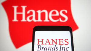 HanesBrands (HBI) logo displayed on a smartphone with red Hanes underwear brand logo displayed in image background