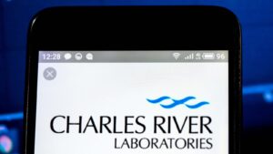 The logo for Charles River Laboratories (CRL) displayed on a smartphone with a blue stock chart in the background.