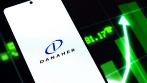 The logo for Danaher (DHR) displayed on a smartphone with a stock chart in the background.