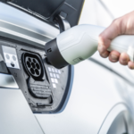 The driver of the electric car inserts the electrical connector to charge the batteries. Electric vehicle charger