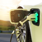 Electric car or EV car charging in station on blurred of sunset with wind turbines in front of car on background. Eco-friendly alternative energy concept. best battery stocks to buy