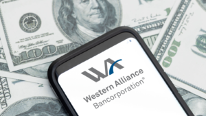 Western Alliance (WAL) financial services company logo on Smartphone screen and dollar banknotes background