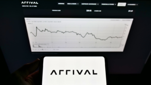 Person holding mobile phone with logo of electric vehicle manufacturer Arrival Ltd. (ARVL) on screen in front of website with chart. Focus on phone display. Unmodified photo.