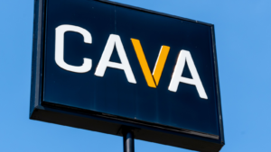Horizontal, medium closeup of "CAVA" outdoor free standing brand and logo signage on a bright sunny day against a clear blue sky.