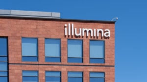 Illumina (ILMN) logo displayed on reddish stone facade building against blue sky background