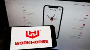 Person holding cellphone with logo of American electric vehicle company Workhorse Group Inc. (WKHS) on screen in front of webpage. Focus on phone display. Unmodified photo.