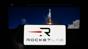 Particular person holding smartphone with model of aerospace company Rocket Lab USA Inc. (RKLB) on video show in front of online page. Focal point on phone prove. Unmodified picture.