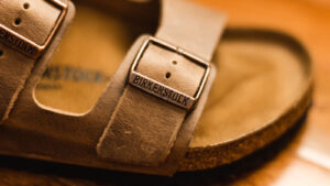 Close-up photo of brown Birkenstock (BIRK) sandal showing brand name on leather strap