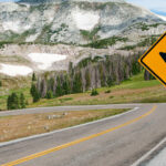A close-up shot of a U-Turn sign with a mountain and highway in the background. Underdog Stocks Set for Turnaround