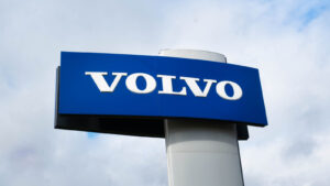 Photo of blue and white Volvo (VLVLY) logo on a car dealership sign with light and cloudy background
