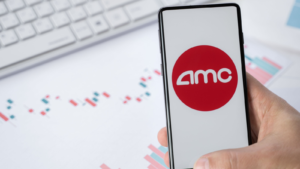 Mobile phone with logo of AMC Entertainment Holdings (AMC). Pumping stock exchange prices by Reddit investors. Playing on market, manipulation. Losses, crisis.