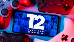 Take-Two Interactive Software, Inc. (TTWO) is an American video game holding company. A smartphone with the Take-Two logo on the screen surrounded by gamepads.