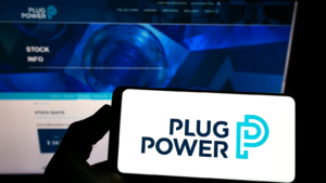 Person holding smartphone with logo of US hydrogen fuel cell company Plug Power Inc. (PLUG) on screen in front of website. Focus on phone display. Unmodified photo.