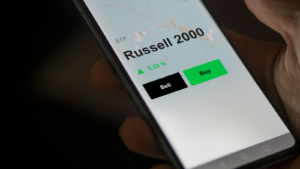 An investor's analyzing the russell 2000 etf fund on a screen. A phone shows the prices of Russell 2000