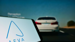 Mobile phone with logo of American autonomous driving company Aeva Inc. on screen in front of business web page. Focus on left of phone display. Unmodified photo.