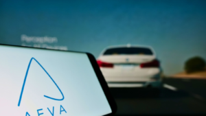 A mobile phone with the logo of American self-driving company Aeva Inc. displayed on the screen in front of the company's webpage. The focus is on the left side of the phone's display. Unedited photo.