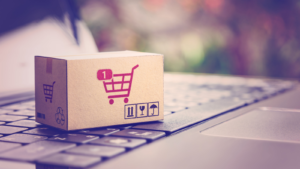 Online shopping / ecommerce and delivery service concept : Paper cartons with a shopping cart or trolley logo on a laptop keyboard, depicts customers order things from retailer sites via the internet. BYON stock