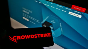 A screen at the front of the site shows a person holding a smartphone bearing the logo of U.S. software company CrowdStrike Holdings Inc. (CRWD). Focus on mobile phone display. Unedited photo.