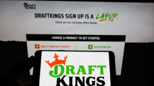 Person holding smartphone with logo of US sports betting company DraftKings Inc. (DKNG) on screen in front of website. Focus on phone display. Unmodified photo.