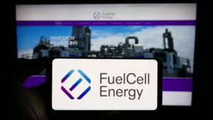Person holding cellphone with logo of US fuel cell company FuelCell Energy Inc. (FCEL) on screen in front of business webpage. Focus on phone display. Unmodified photo.