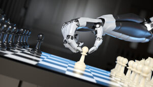 An image of a white and grey robotic hand moving a white pawn on a chess board in a grey room.