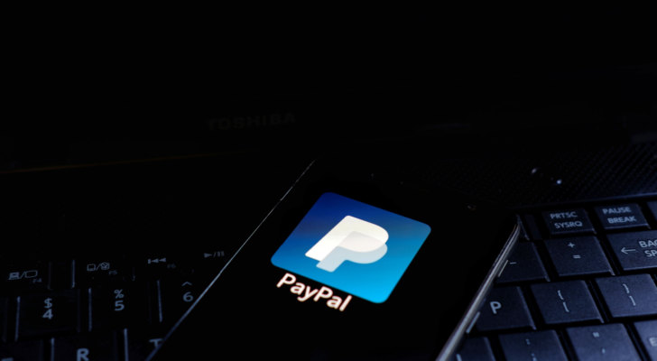 PayPal Holdings, Inc. (PYPL) icon displayed on smartphone with keyboard background. is an American multinational financial technology company operating an online payment
