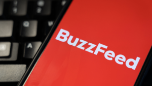 Buzzfeed (BZFD) logo on a phone with a keyboard in the background. Buzzfeed layoffs