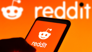 In this photo illustration the Reddit logo seen displayed on a smartphone and on the background. RDDT and the Reddit IPO