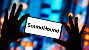 このイラスト写真では、SoundHound のロゴがスマートフォンに表示されています。 SOUN株