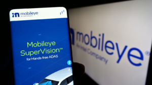 Person holding cellphone with website of Israeli autonomous driving company Mobileye (MBLY) on screen in front of logo. Focus on center of phone display. Unmodified photo.