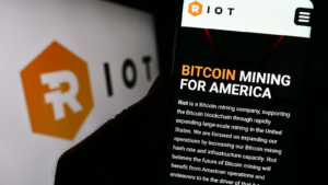 Person holding cellphone with website of U.S. Bitcoin mining company Riot Platforms Inc. on screen with logo. Focus on center of phone display. Unmodified photo.
