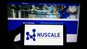 Person holding mobile phone with logo of American nuclear power company NuScale Power LLC on screen in front of web page. Focus on phone display. Unmodified photo. SMR stock